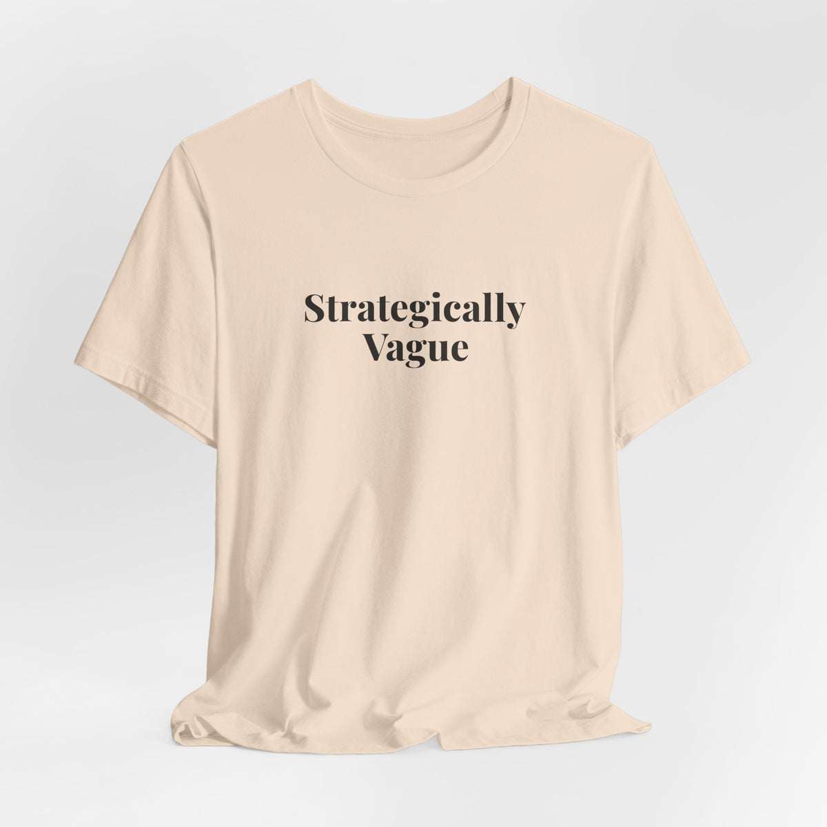 Soft cream “Strategically Vague” tee on a hanger