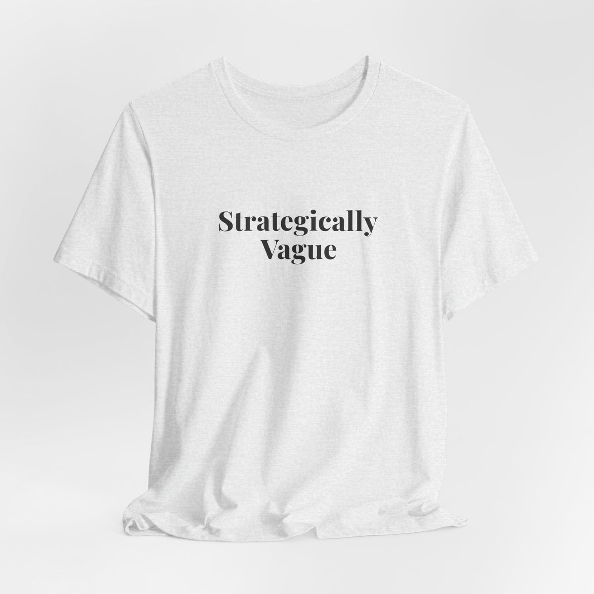 The ash “Strategically Vague” tee hanging on a hanger